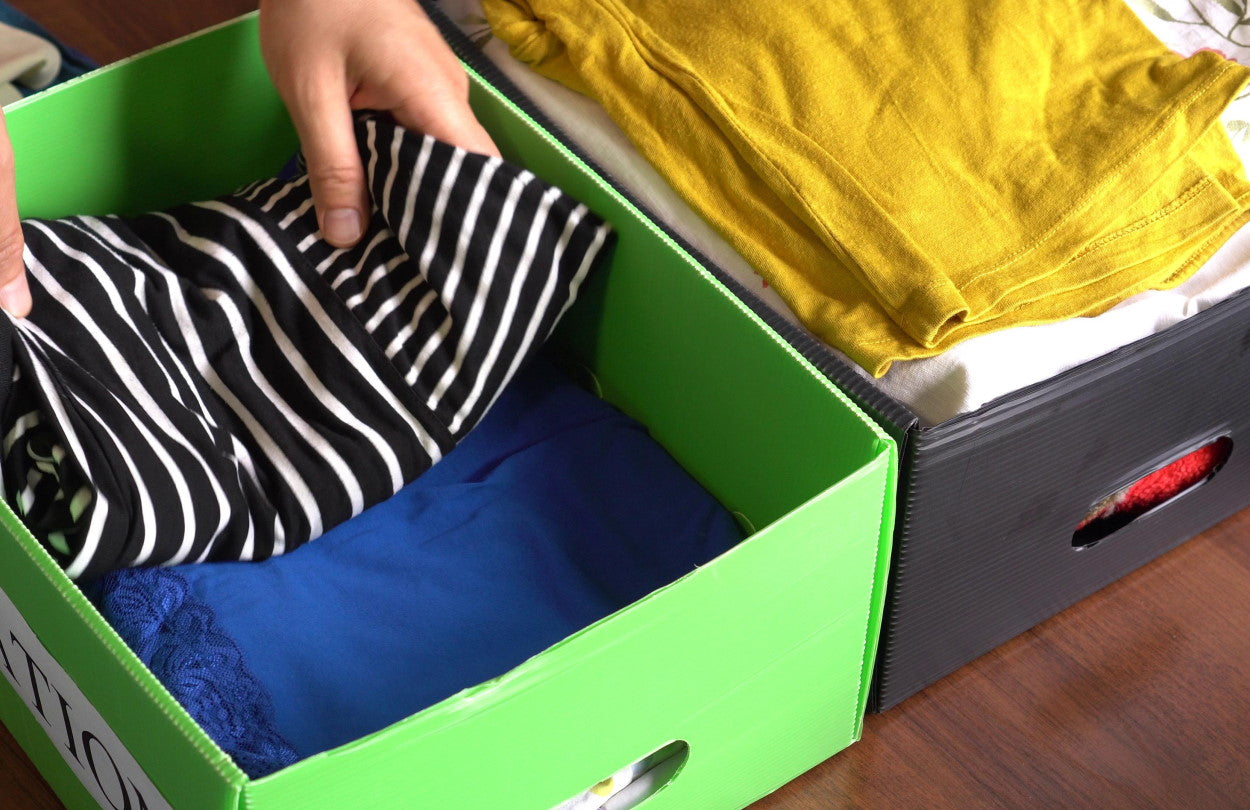 Clothes being placed into colorful storage boxes