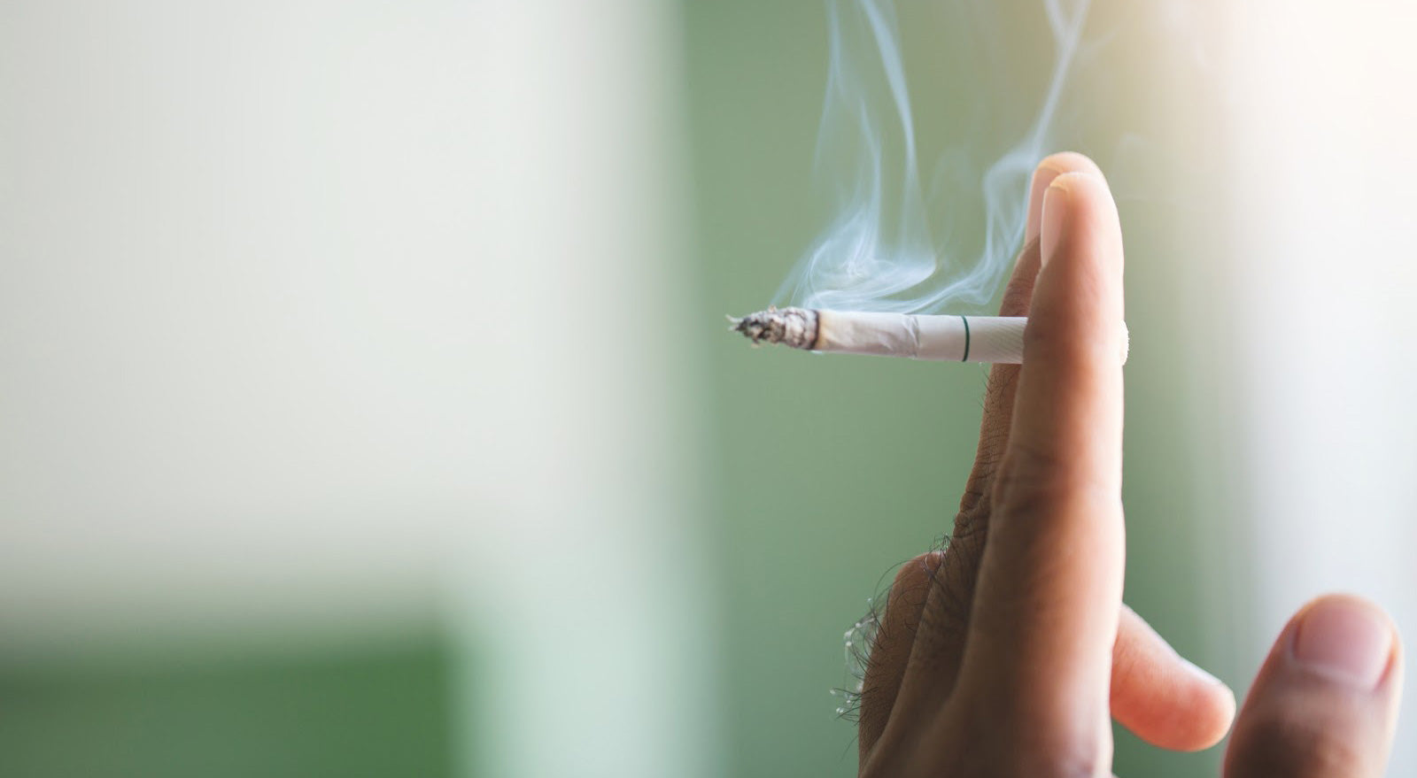 A hand holding a burning cigarette