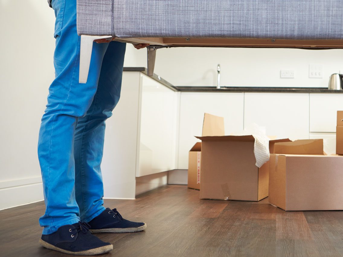 Person moving a couch in new home