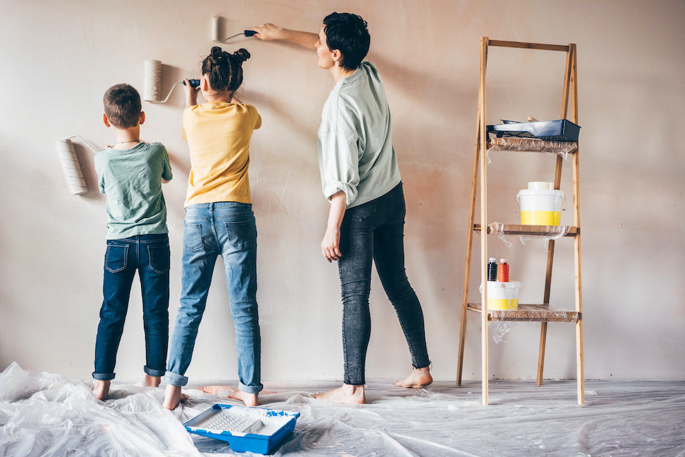 Mother with young daughter and son painting a wall together