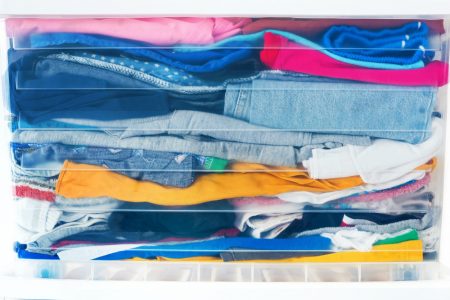 A variety of clothes packed tightly in a plastic tub