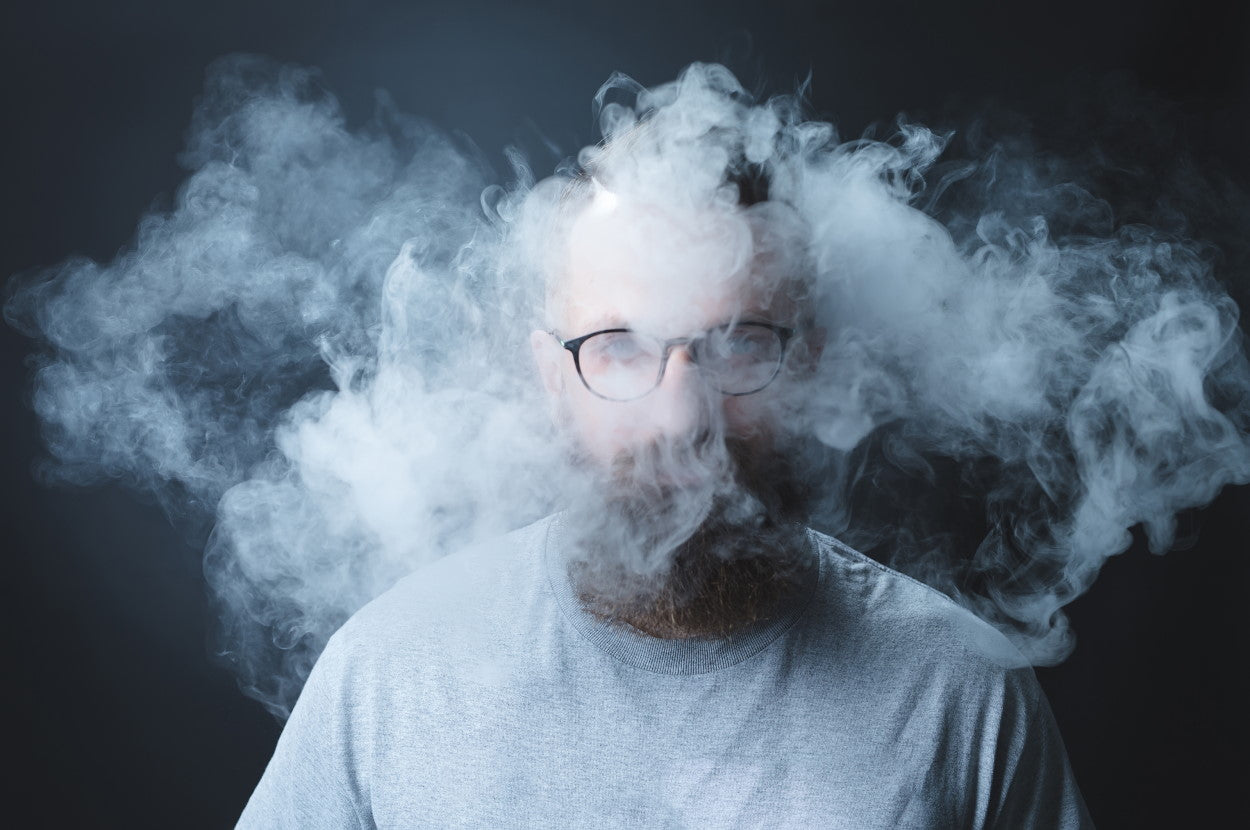 A man in glasses and beard with head obscured by smoke