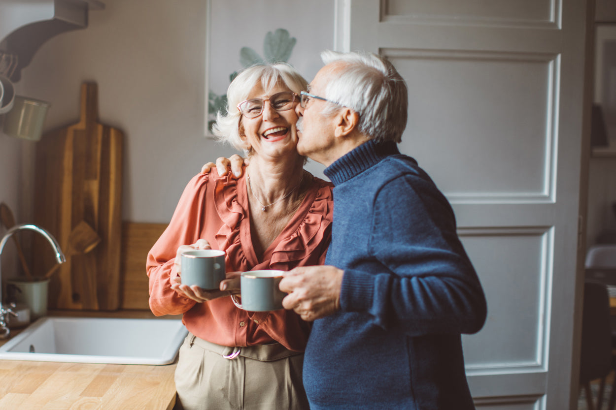 Elderly man kissing his wife's cheek as she smiles