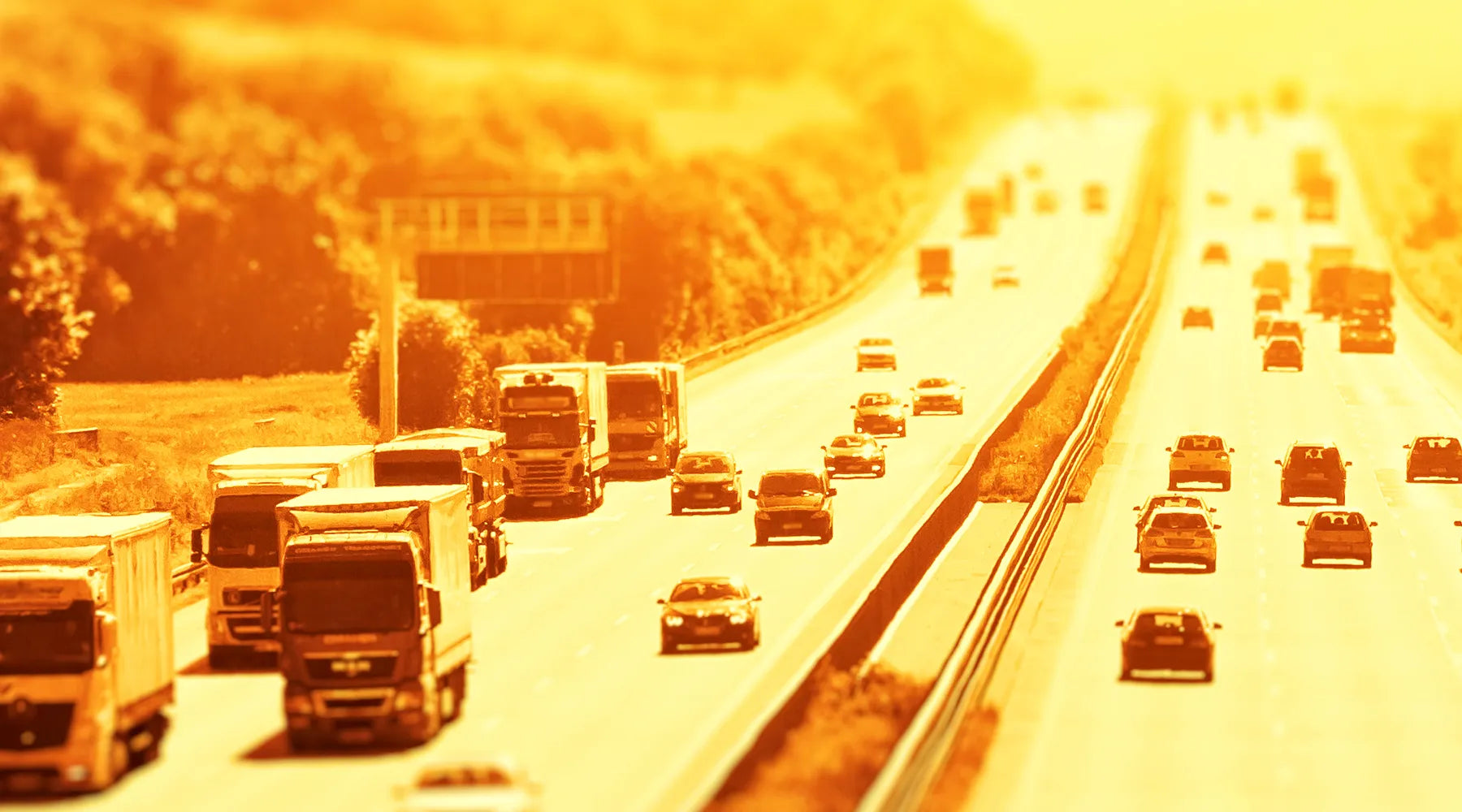 Cars and trucks drive on the highway under an oppressively hot sun.