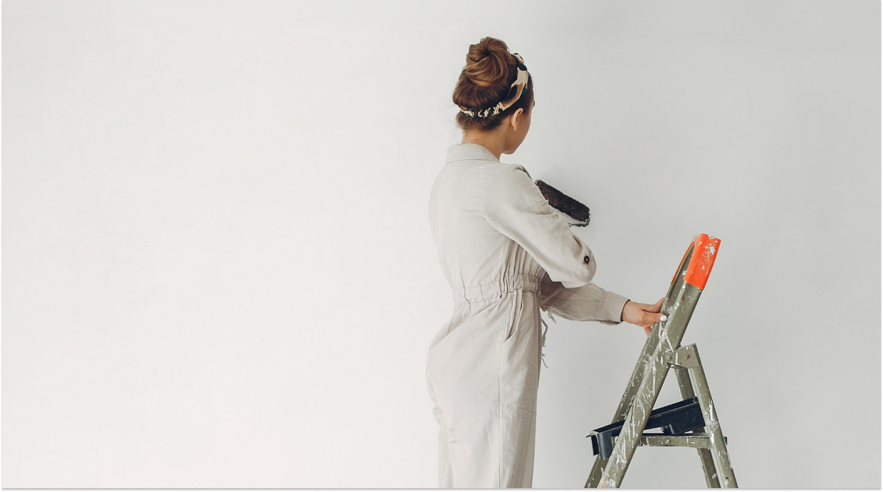 Woman standing on ladder painting a wall
