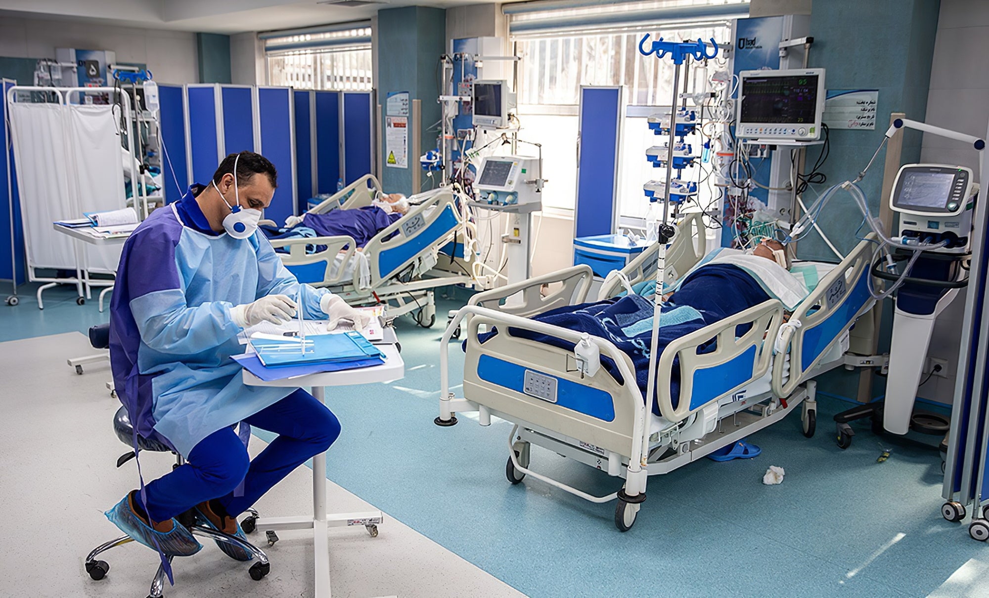 Medical professional in scrubs and protective equipment in a hospital intensive care unit