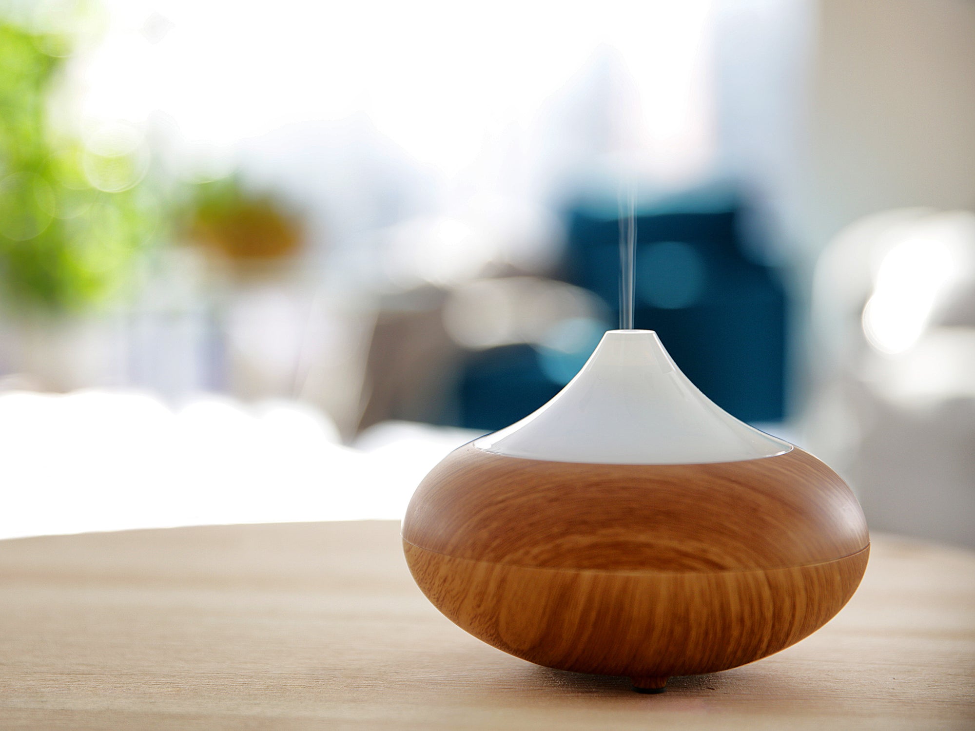 A diffuser sits on top of a table, releasing diffused scents into the room.