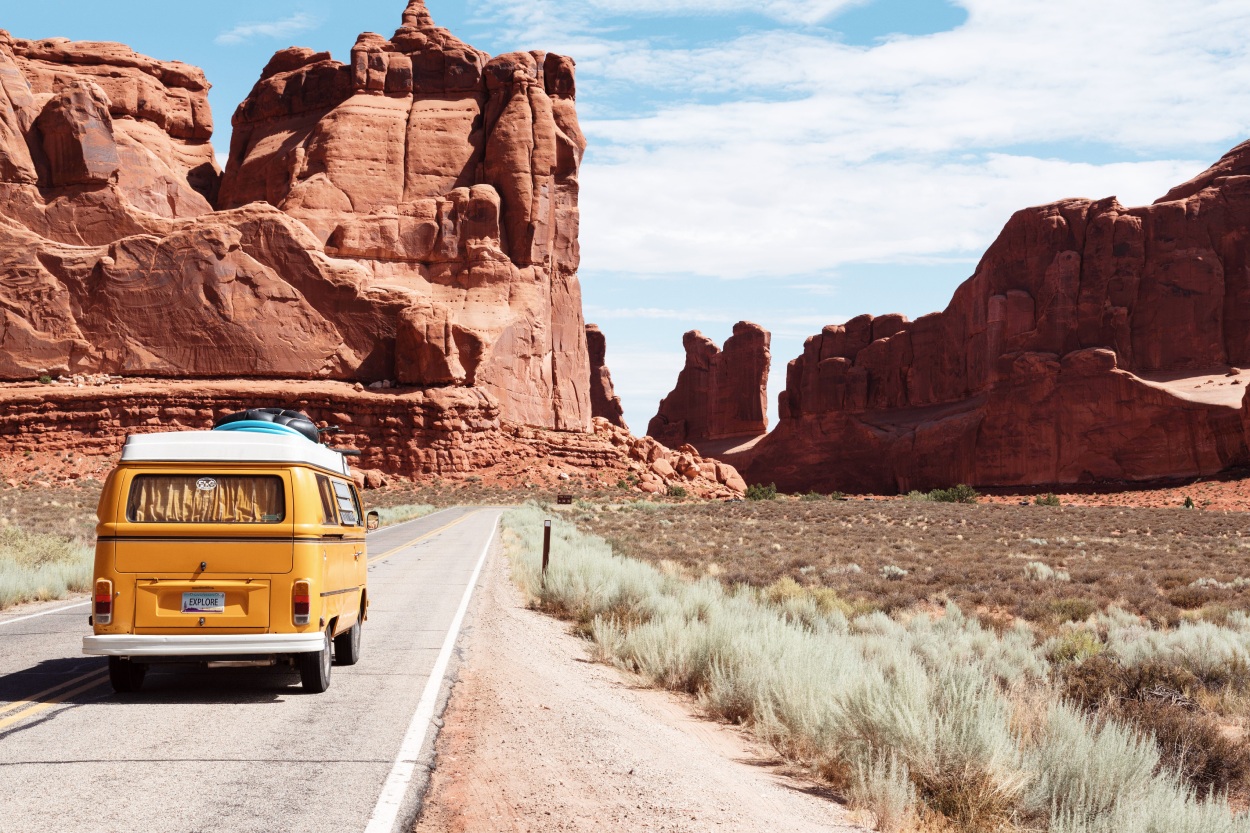 A yellow camper van driving through a desert landscape