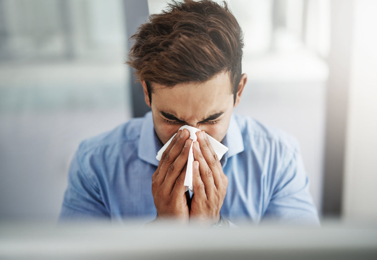 man with cold blowing his nose 
