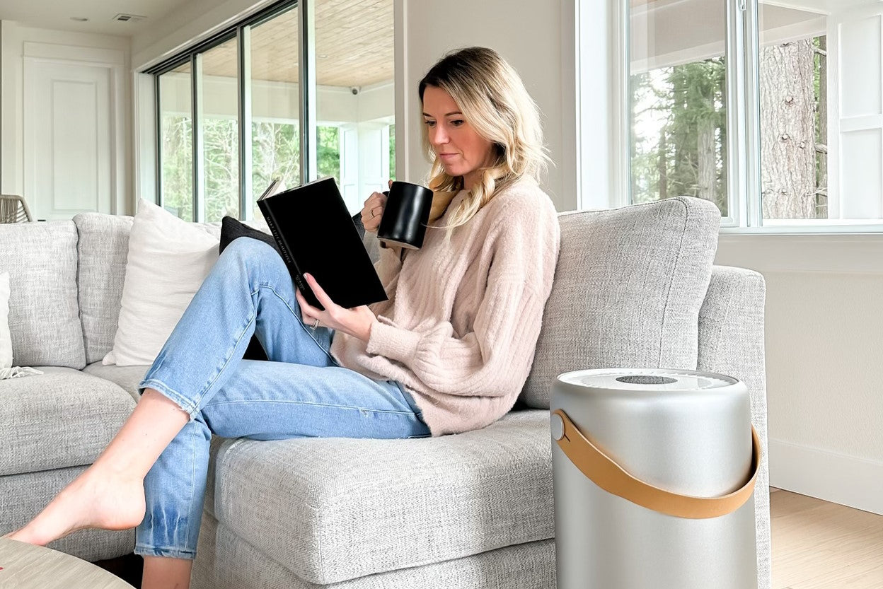 Mom relaxing on the couch with a book and her Molekule Air Pro