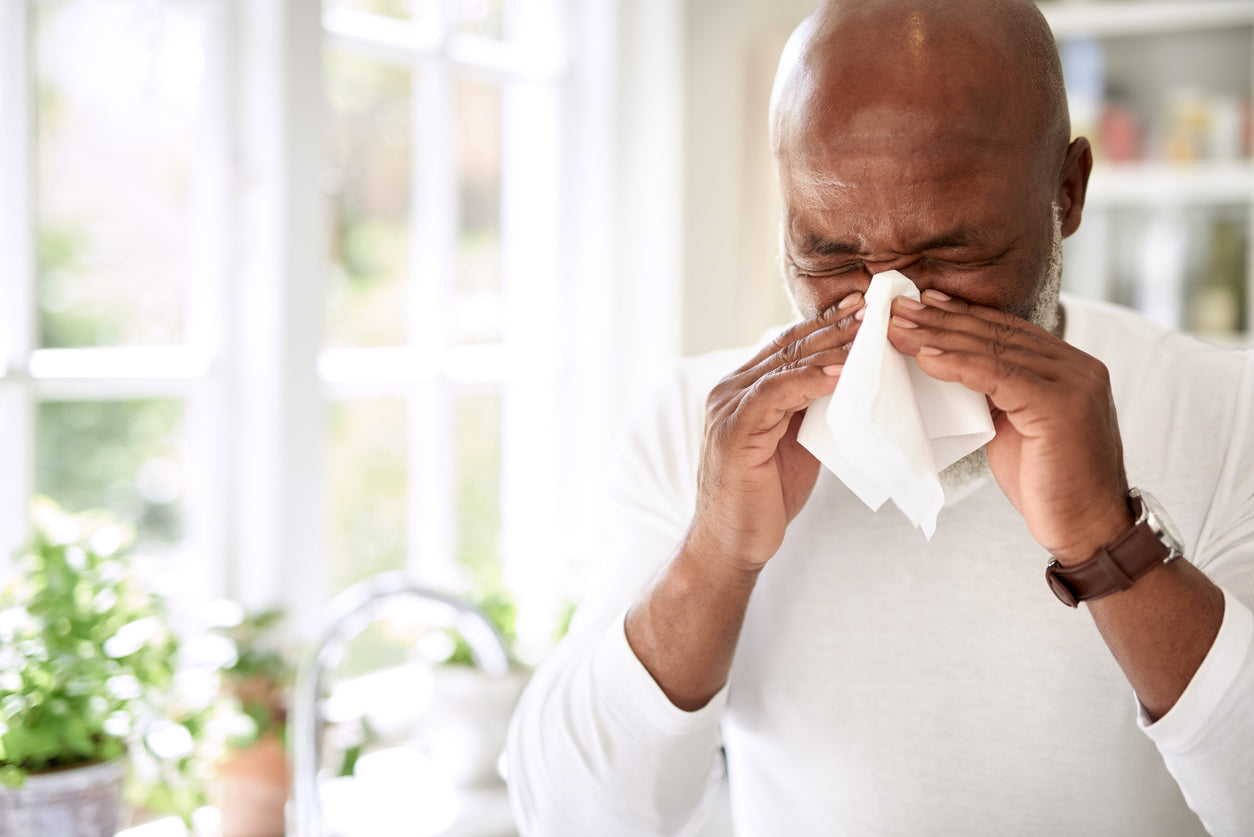 man with allergies sneezing with tissue