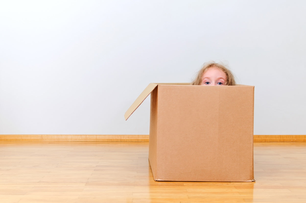 Child peeking out of a cardboard box