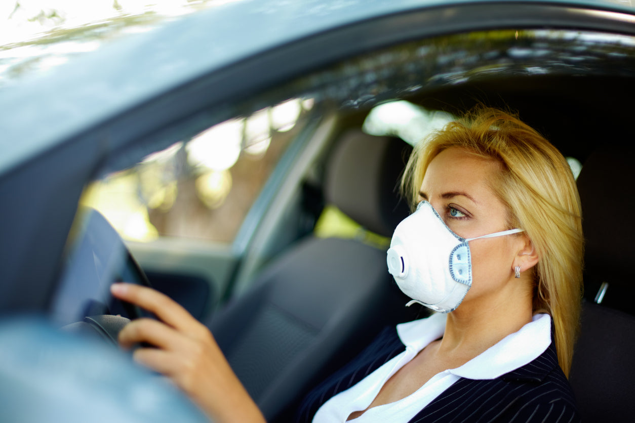 Woman wearing protective face mask in her car
