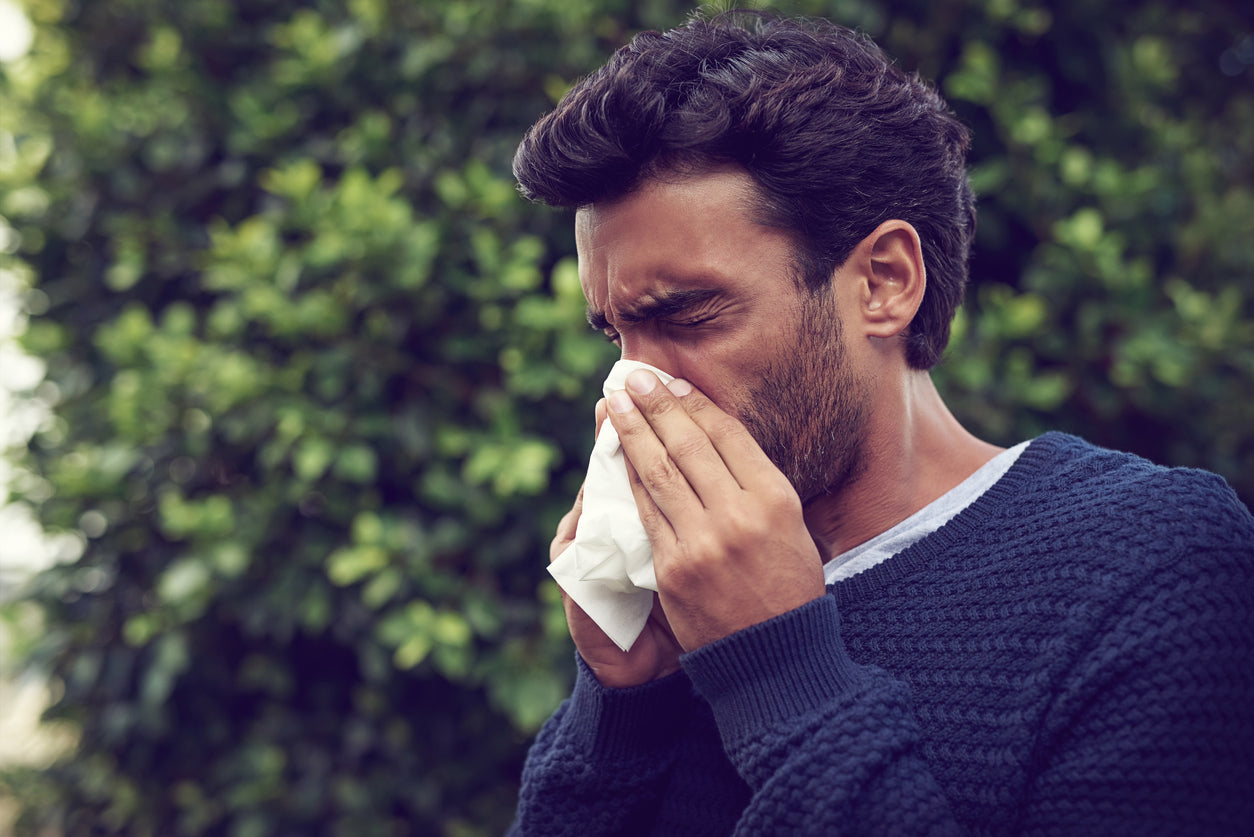 Man with allergies sneezing into a tissue