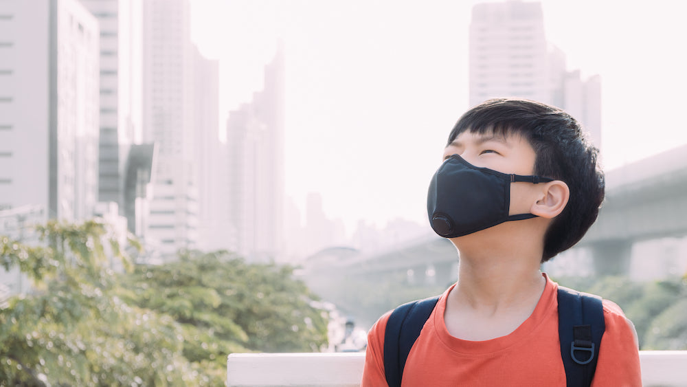 Masked boy looking at the sky with cityscape in the background