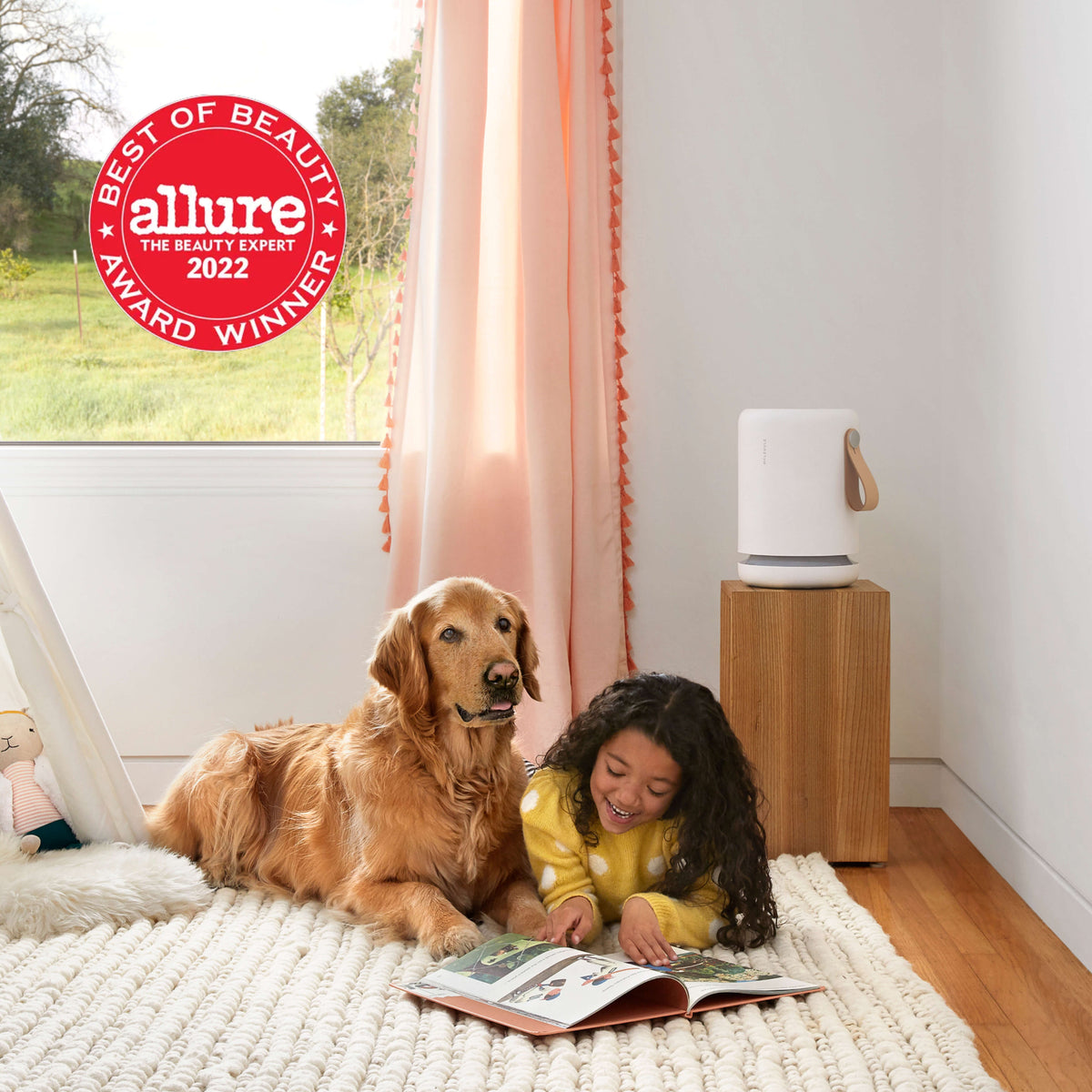 Child and dog laying on the floor reading a book in front of an Air Mini+ air purifier